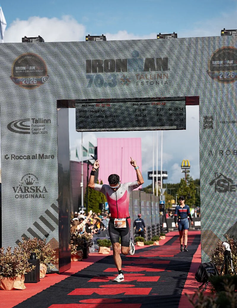 Akshit crossing the Ironman 70.3 Tallinn finish line, arms raised