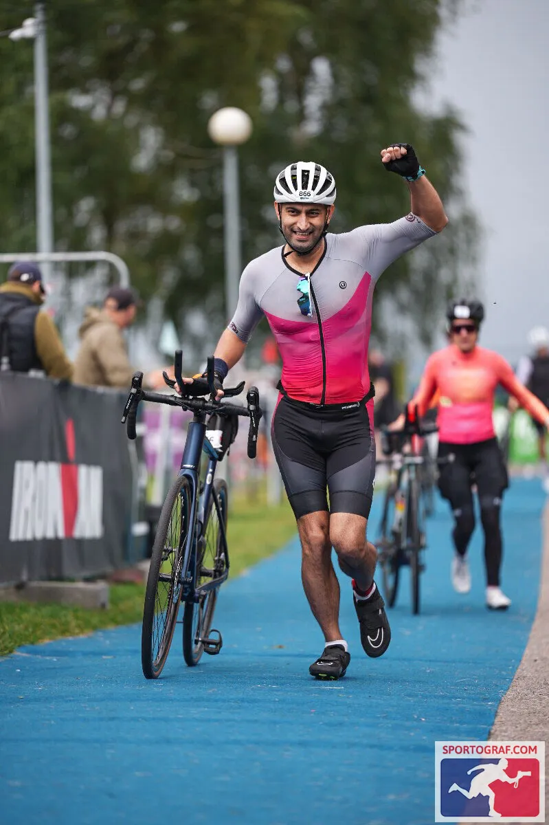 Akshit walking his bike up the Ironman carpet, fist raised